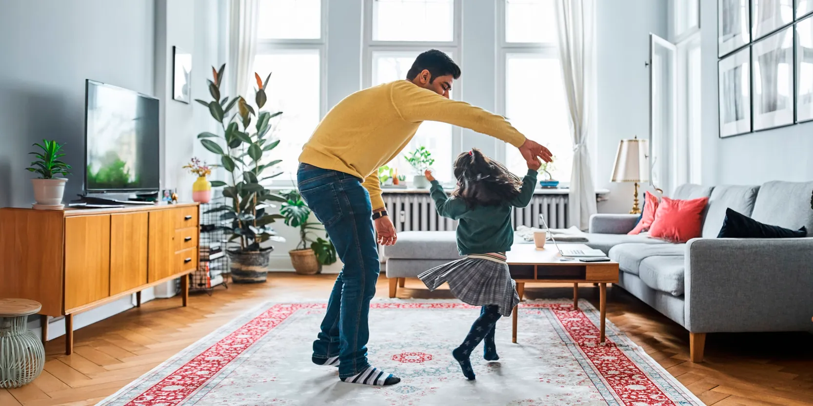 Man dancing with child in living room